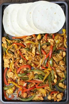 chicken fajitas and tortillas on a baking sheet with pita bread