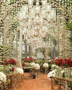 an outdoor ceremony with flowers and chandeliers