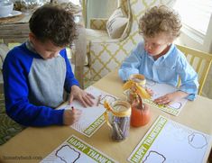 two young boys sitting at a table doing crafts