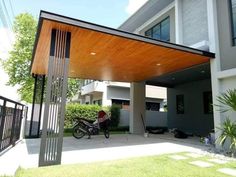 a motorcycle is parked under an awning in front of a house with trees and bushes