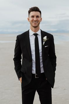 a man in a suit and tie standing on the beach