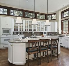 a large kitchen with white cabinets and an island in the middle, surrounded by wooden flooring