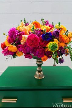 a vase filled with colorful flowers sitting on top of a green table