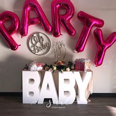 there are balloons that spell out the word baby in front of a table with presents on it