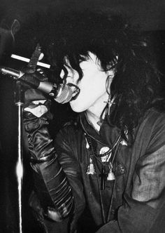 a woman singing into a microphone while wearing leather gloves