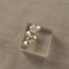 two engagement rings sitting on top of each other in front of a ring box with the wedding band