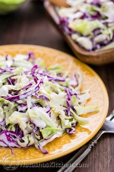 a yellow plate topped with coleslaw on top of a wooden table