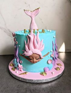 a birthday cake decorated with an image of a mermaid sitting on top of the cake