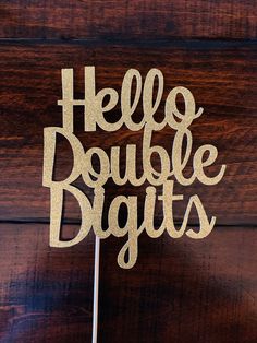 a cake topper with the words hello double digits on it, in gold glitter