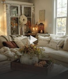 a living room filled with lots of furniture next to a window covered in fall decorations