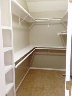 an empty walk in closet with white shelves