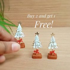 three small white christmas trees with red bows on them and the words buy 2 and get 1 free