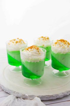 four glasses filled with green liquid and topped with whipped cream, sprinkled with orange zest