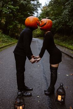 two people holding hands with pumpkins on their heads