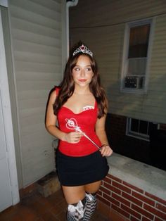 a woman in a red shirt and black skirt posing for the camera with a wand