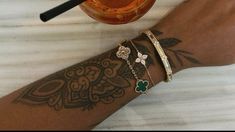 a woman's arm with tattoos and bracelets next to a jar of honey