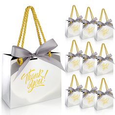 white gift bags with silver ribbons and thank you tags in gold lettering on them are shown next to each other