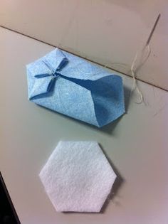 an origami piece of paper with a tie on it sitting next to a hexagonal object