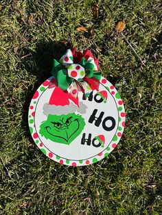 a christmas ornament on the grass with a green and red bow around it