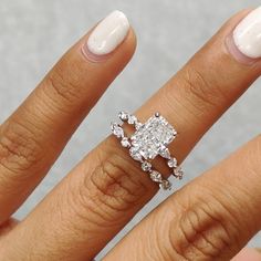 a woman's hand with a diamond ring on top of her finger and white nail polish