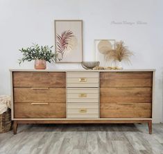 a wooden dresser with drawers and plants on top