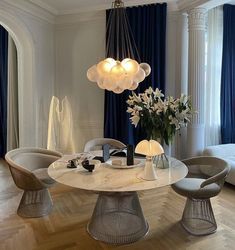 a dining room table with chairs and a chandelier hanging from it's ceiling