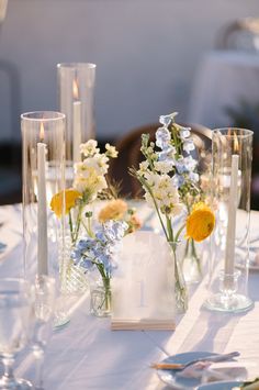 a table topped with lots of vases filled with different types of flowers and candles