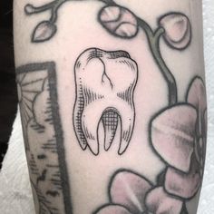 a tattoo with a tooth and flowers on it