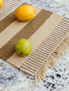 two lemons sitting on top of a table next to a green and yellow fruit