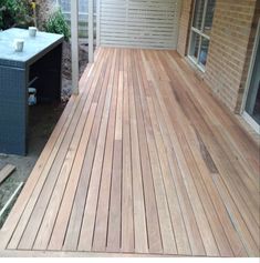 a wooden deck in front of a house with an air conditioner on the side