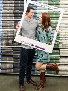 a man and woman standing next to each other holding up a photo frame