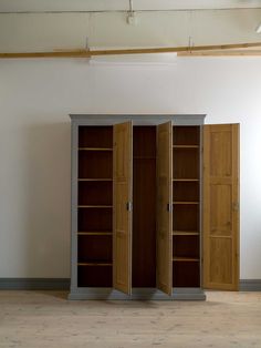 an empty room with three wooden doors and two open bookshelves on the floor