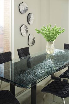 a glass table with black chairs and a vase filled with flowers on the top shelf