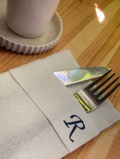 a fork and knife on top of a napkin next to a cup