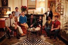 a group of men sitting around each other in a living room with zebra print rug