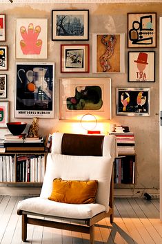 a white chair sitting in front of a wall filled with pictures