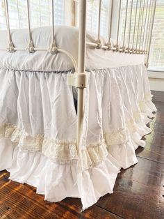 a white crib with ruffled bedspread on the bottom and side rails