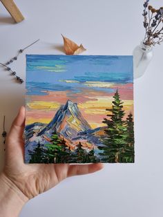 a painting of a mountain with pine trees in the foreground and an acrylic paint brush