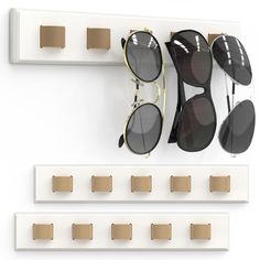 three pairs of sunglasses are hanging on the wall with pegs to hold them in place