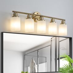 a bathroom vanity light with three lights on it and a mirror in front of it