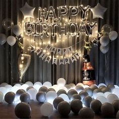 a birthday party with balloons and lights on the wall, including a bottle of booze