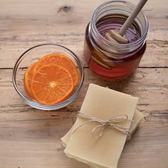 an orange slice next to a jar of honey and some soap on a wooden table