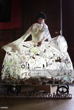 a woman sitting on top of a large piece of art that is made out of paper