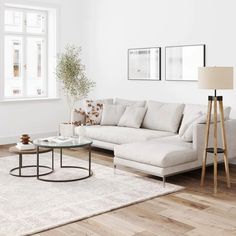 a living room with white walls and wooden floors is furnished with a large sectional sofa