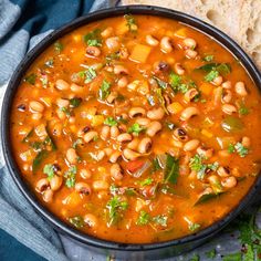 a bowl filled with beans and greens next to bread