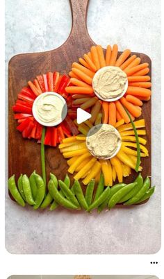 an assortment of vegetables and dips on a cutting board