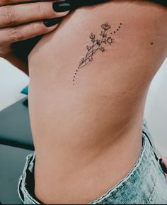 a woman's stomach with a flower tattoo on her lower back and the side