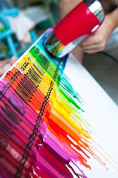 a person using a paint brush to create a rainbow - hued design on a piece of paper