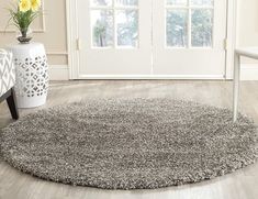 a large round rug on the floor in front of a white chair and vase with yellow flowers