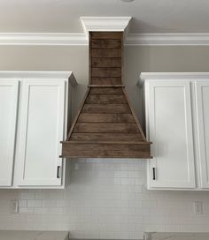 a kitchen with white cabinets and a wood stove hood